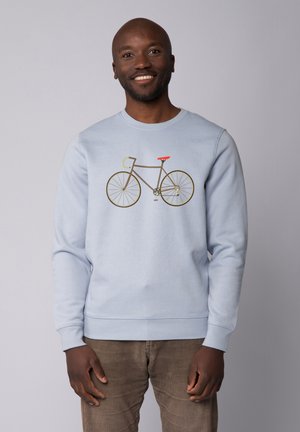 Helles blaues Sweatshirt mit einer Fahrrad-Grafik, das einen braunen Rahmen und grüne Lenker zeigt, ergänzt durch einen roten Sitz. Weiche Textur und Rundhalsausschnitt.