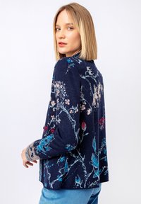 Zils, rozā un sarkans ziedu raksts uz jūras spēku krāsas kardigāna. Garas piedurknes ar strukturētu dizainu. Brīvs piegriezums, atvērta priekšpuse. Mīksts materiāls.