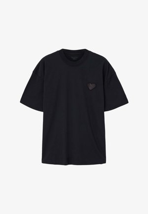 Sort bomulds-T-shirt med korte ærmer og rund halsudskæring. Har en lille sort hjerte grafik på venstre brystområde.