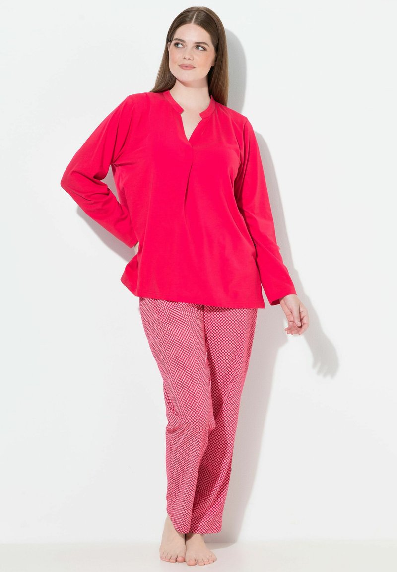 Maglia rossa a maniche lunghe con colletto a punta abbinata a pantaloni rosa a fantasia con un design a diamante, realizzati in un tessuto morbido e liscio.