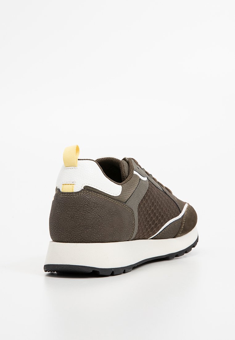 Braune Sneaker mit einer strukturierten Oberseite, Mesh-Einsätzen, weißen Akzenten und einem gelben Tab an der Ferse. Verfügt über eine leichte Sohle.