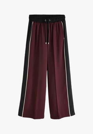 Plati kojinės su bordo korpusu, juodais šonų paneliais ir baltais apvadais. Turi elastingą juosmenį su raišteliu. Lygus paviršius.