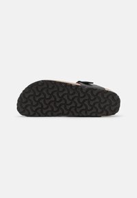 Suela de zapato negra con un patrón de ondas texturizado, que presenta una forma redondeada y una ligera elevación en el talón. Sin adornos adicionales.