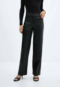 Pantaloni larghi in finta pelle nera con vita alta, dotati di chiusura a bottone, passanti per cintura e una texture liscia e lucida.