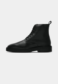 Black leather ankle boots with a round toe, lace-up design, flat rubber sole, and a pull tab on the back for easy wear.