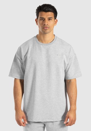 Lys grå oversized T-shirt lavet af blødt, åndbart stof. Har en rund halsudskæring og korte ærmer, med diskret branding på brystet.