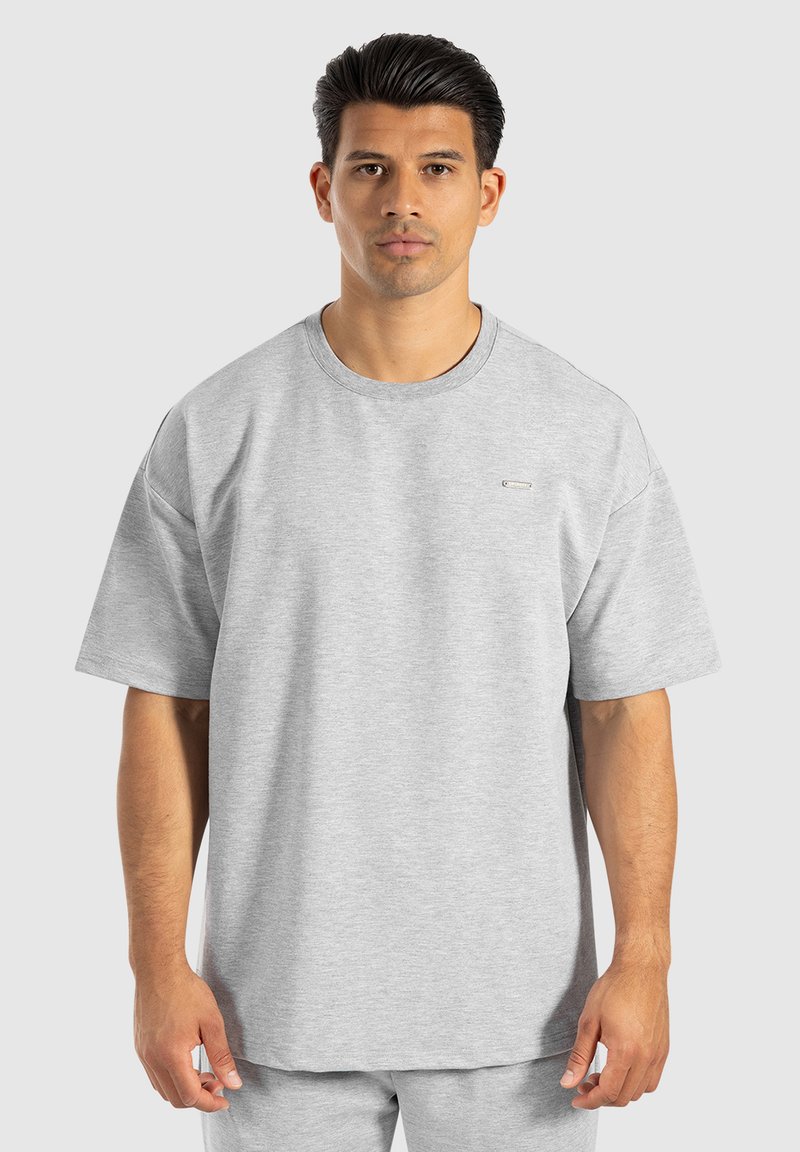 T-shirt oversize grigio chiaro realizzato in tessuto morbido e traspirante. Presenta un collo rotondo e maniche corte, con un branding discreto sul petto.