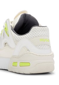 Sneaker bianco con materiali in mesh e pelle, dettagli in neon giallo, tallone imbottito e suola texturizzata. Presenta il logo "HUGO" sul lato.