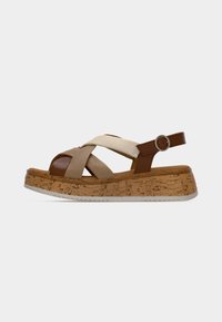 Sandale compensée marron et beige avec des brides croisées et une boucle ronde sur une semelle plateforme texturée liège.