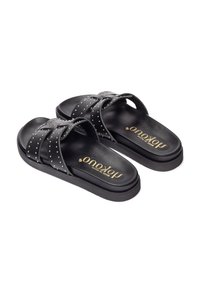 Sandali neri con fasce incrociate e borchie in argento. Realizzati in pelle con una suola interna testurizzata e una suola piatta bassa.