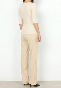 Beige geribd top met driekwarts mouwen gecombineerd met beige wijde broekspijpen. De outfit heeft een aansluitend ontwerp en een gladde stoftextuur.