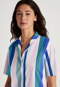 Camicia a maniche corte con bottoni, caratterizzata da strisce verticali blu, rosa e turchese. Tessuto morbido con colletto classico e vestibilità rilassata.