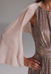 Châle en chiffon rose pâle drapé sur une robe à rayures multicolores scintillantes, dotée d'une taille cintrée et d'une jupe fluide.