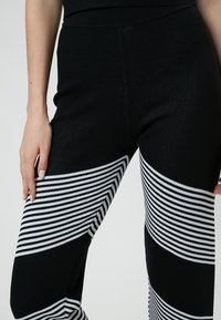 Zwart-wit gestreepte legging van een zachte, rekbare stof, met gedurfde horizontale strepen en een aansluitend ontwerp op de onderbenen.
