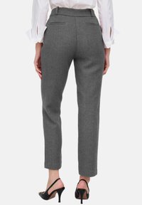 Graue maßgeschneiderte Hosen mit Hahnentrittmuster, schmaler Schnitt, Seitentaschen und Gürtelschlaufen, kombiniert mit schwarzen High Heels.