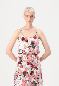Floral sleeveless dress with pink, red, and green patterns, elastic waist, and a gathered neckline. Made of light, textured fabric.