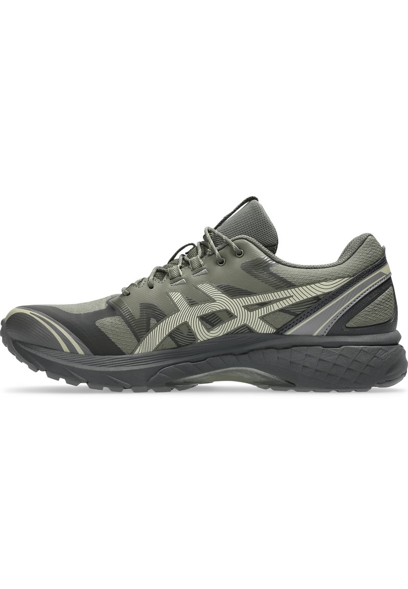 Grüner Sportschuh mit einem strukturierten Mesh-Obermaterial, geschwungenem Design, gemusterten Akzenten und einer schwarzen, robusten Sohle für Traktion. Schnürsenkel für einen sicheren Sitz.