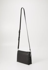 Fekete keresztbody táska szőtt textúrával, hosszú állítható pánttal és cipzáras zárással, sima fehér háttér előtt elhelyezve.