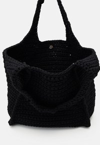Zwarte geweven tas met een open bovenkant, gemaakt van textuurmateriaal. Twee stevige schouderbanden en een knoopsluiting detail aan de binnenkant.