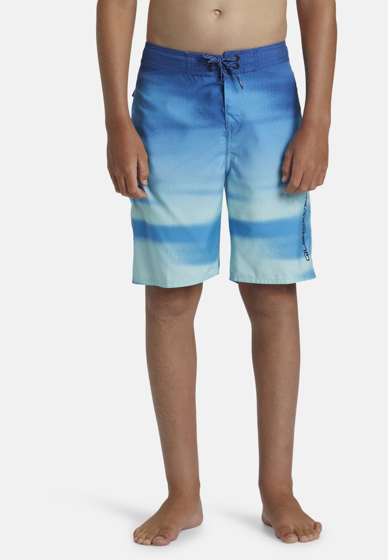 Modré gradientové plavky, ktoré majú jemnú textúru, pás na šnúrku a logo na boku. Vzor prechádza z tmavomodrej do svetlomodrej.