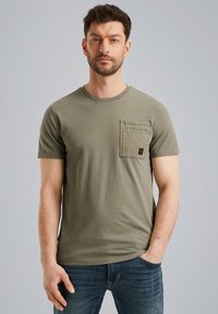 Camiseta de manga corta de color verde oliva, fabricada en algodón, con un bolsillo en el pecho izquierdo y un cuello redondo. Textura suave y ajuste casual.