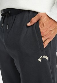 Navyblauwe joggingsbroeken van een zachte katoenmix, met een tailleband met trekkoord en zijzakken. "BILLABONG" logo in crèmekleurige borduring aan de voorkant.