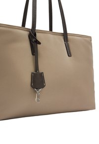 Beżowa torba na ramię z ciemnymi uchwytami, o gładkiej teksturze, kontrastowym przeszyciu i uchwytem na breloczek przymocowanym z boku.