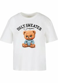 Hvid bomuldstrøje med grafik af en bamse i en blå mønstret sweater med teksten "UGLY SWEATER Season" ovenfor.