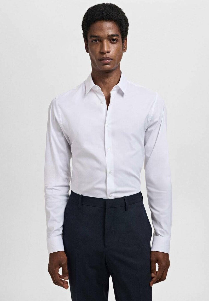 Witte blouse met lange mouwen, klassieke kraag, knoopsluiting aan de voorkant en een gladde textuur, gecombineerd met donkergekleurde broek.