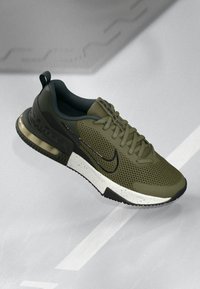 Olive green Nike Air Max sneaker with black swoosh, speckled white midsole, and visible air cushion on a gray background.
