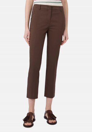 Pantaloni marroni slim fit corti abbinati a sandali in pelle marrone scuro con nappine e top smanicato a righe.