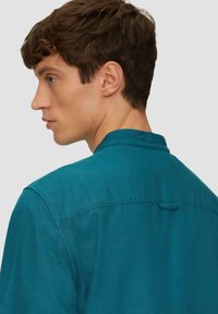 Teal shirt gemaakt van lichtgewicht stof, met een klassieke kraag, achteryoke en subtiele textuur. Schoon ontwerp zonder zichtbare patronen.