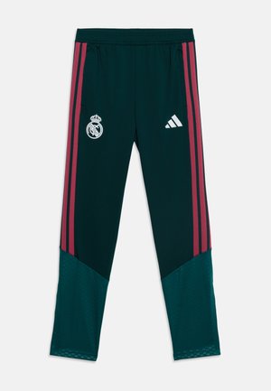 Ciemnozielone spodnie sportowe z bordowymi paskami po bokach, elastycznym pasem, logo Real Madrid na lewym udzie oraz logo Adidas na prawym udzie.