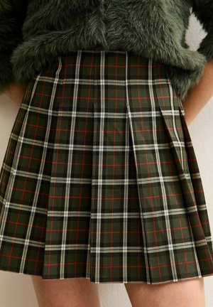 Falda plisada a cuadros verdes con rayas rojas y blancas, hecha de una tela texturizada, que presenta una cintura alta y un patrón distintivo.