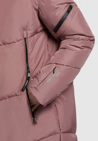 Roze pufferjack met gestikte ontwerpen, voorzien van zwarte ritsaccenten en een klein zwart ritszakje op de mouw. Soepele textuur.