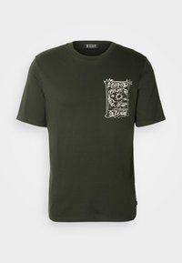 Mørkegrøn bomulds t-shirt med rund hals, korte ærmer og et hvidt grafikdesign på venstre bryst, der indeholder abstrakte elementer.