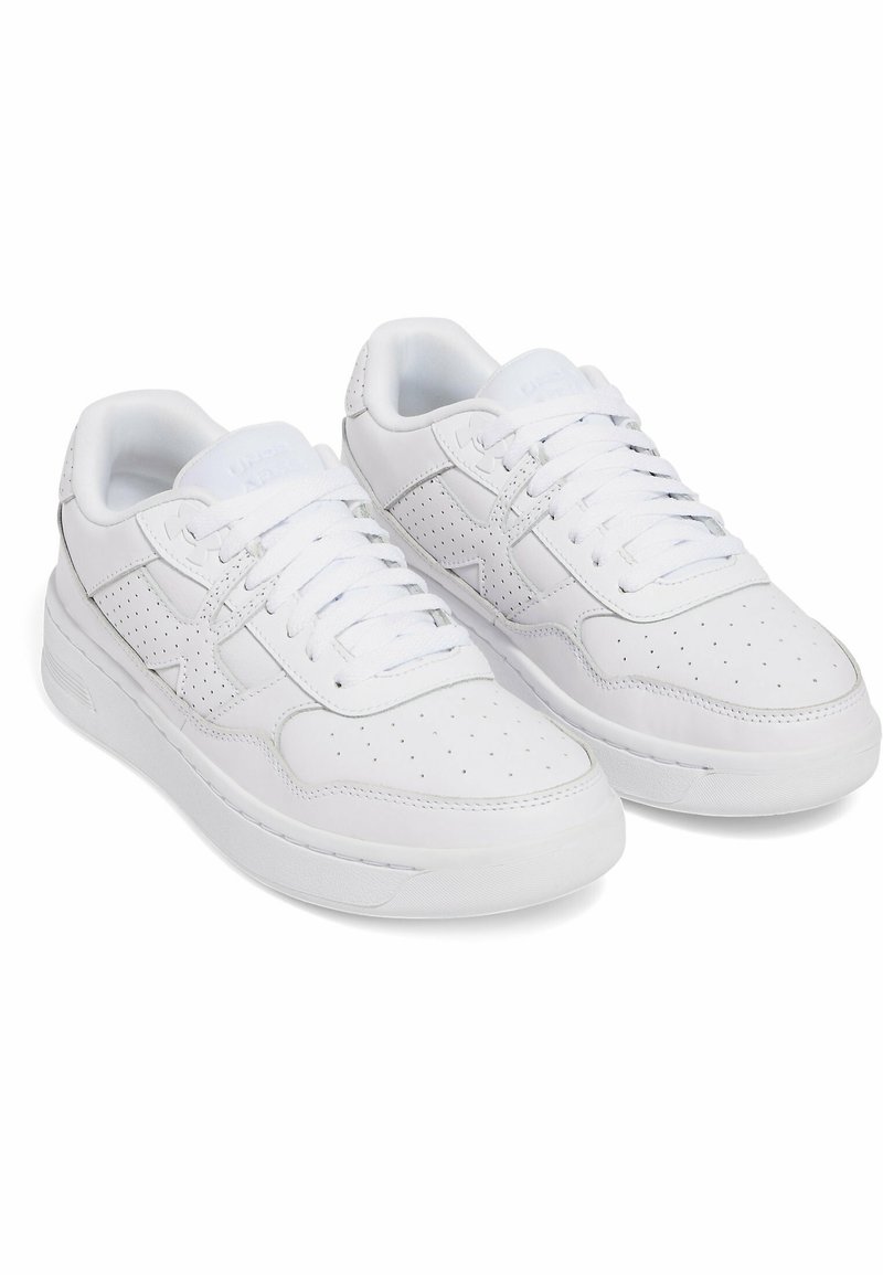 Zapatillas blancas de cuero con acentos perforados, diseño con cordones, cuello acolchado y una suela de goma gruesa. Estética minimalista.