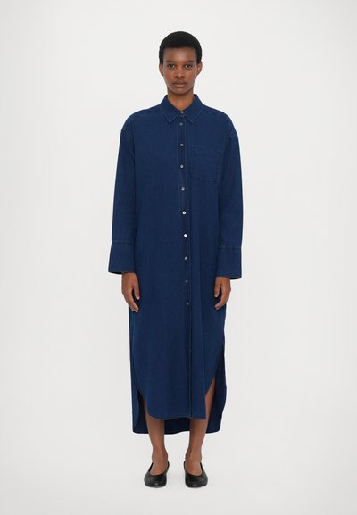 Mørkeblå denimskjortekjole med knaplukning foran, brystlomme, lange ærmer og sideslids for bedre bevægelsesfrihed.