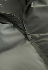 Mörkgrön zip-up jacka i smidigt och lätt material. Har en plastdragkedja och en uppstående krage.