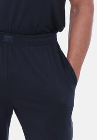 Granatowe dresy wykonane z miękkiego materiału, z elastycznym pasem, bocznymi kieszeniami i gładką fakturą.