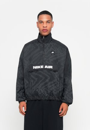 Black jacket with a high collar, featuring a textured pattern, front zip, and "NIKE AIR" logo in white across the chest.