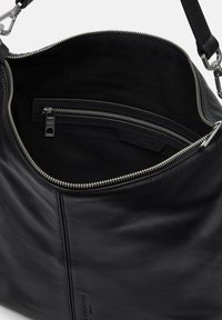 Borsa a mano in pelle nera con una texture morbida, dotata di chiusura con zip, tasca interna con zip e un design elegante con hardware minimale.
