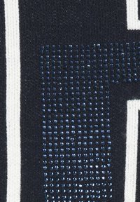 Marineblauer Stoff mit weißen vertikalen Streifen; verfügt über einen strukturierten Bereich kleiner, glänzender blauer Strasssteine, die in einem Farbverlauf angeordnet sind.