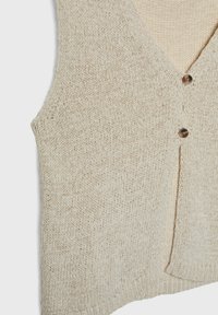 Gilet sans manches en tricot beige avec col en V et deux boutons marron sur le devant.