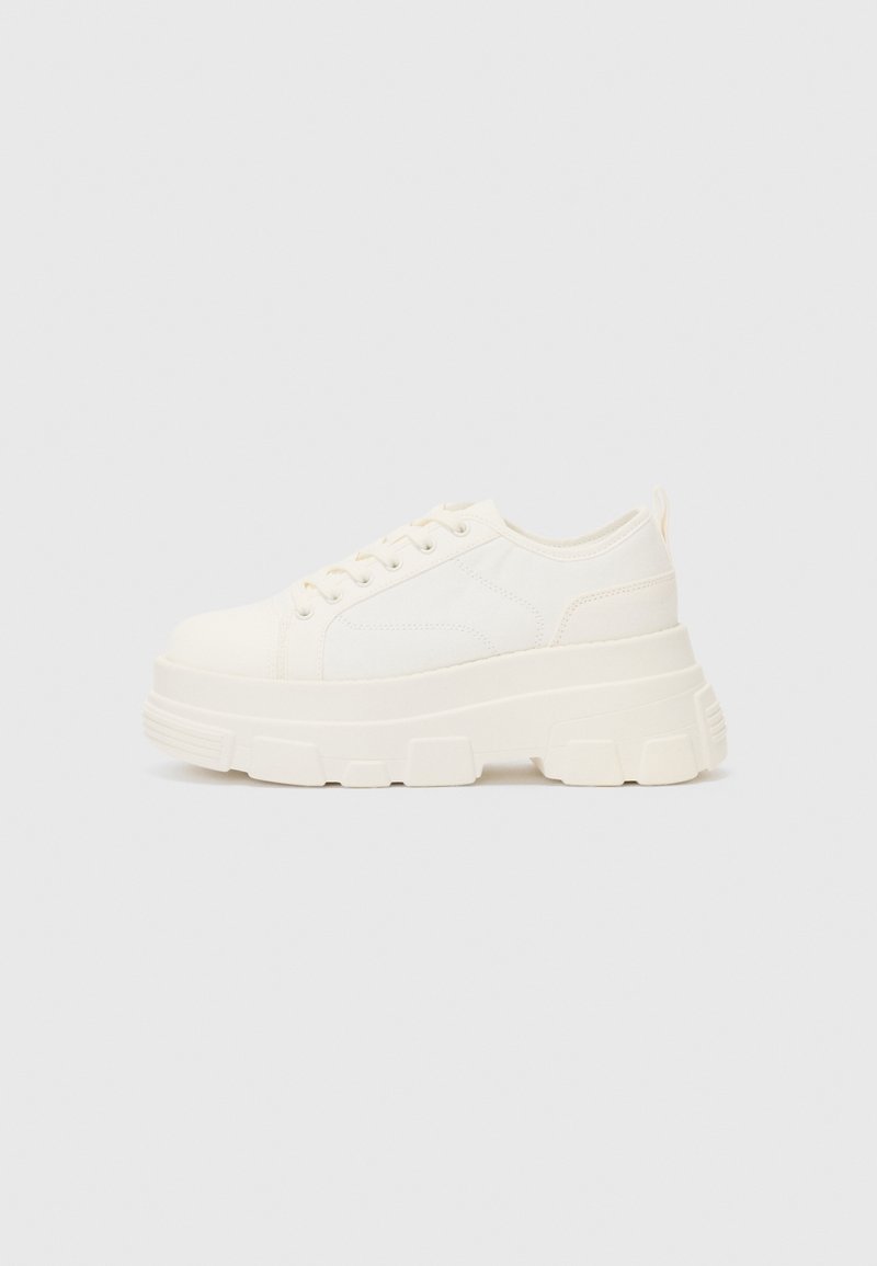 Weiße Leinensneaker mit einer massiven Sohle, abgerundeter Spitze und fünf Ösen für Schnürsenkel. Hinterer Tab für ein einfaches Anziehen. Glatte Textur, minimalistisches Design.