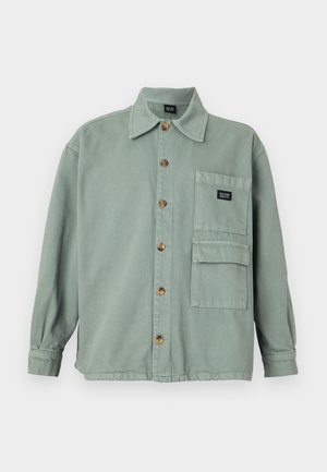 Green canvas shirt jacket with a collared neck, front button closure, and two front pockets. Features wooden buttons and a logo patch.