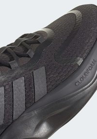 Scarpa da ginnastica nera con upper testurizzato, intersuola liscia, lacci piatti e branding visibile sul lato. Ammortizzazione Cloudfoam indicata.