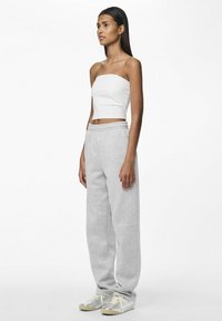 White cropped tube top, gray sweatpants, and silver sneakers. The pants feature an elastic waistband and soft, textured fabric.