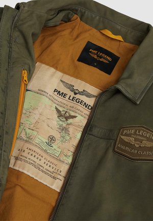 Groene jas met bruine voering met PME Legend-patches en een gedetailleerde vintage-stijl kaartafdruk aan de binnenkant van de jas.