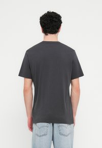 Γκρι κοντομάνικο μπλουζάκι με στρογγυλή λαιμόκοψη, κατασκευασμένο από βαμβάκι. Λείο ύφασμα χωρίς εμφανή γραφικά ή σχέδια, εφαρμοστό σχήμα.